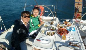 A couple having a nice meal of traditional greek dishes inside barca's boat at Santorini