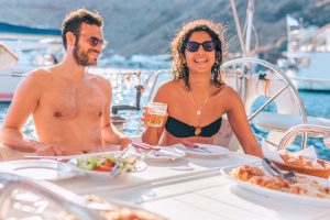 A couple having a nice meal of traditional greek dishes inside barca's boat at Santorini